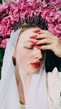 A woman in a crown and veil with red nails poses against vibrant pink peonies. Regal elegance.