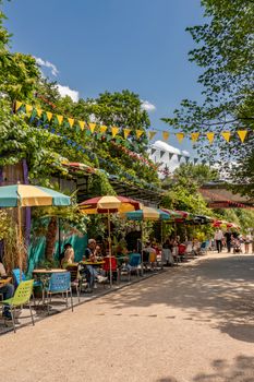 Vibrant outdoor cafe with colorful umbrellas and bunting on a sunny day.