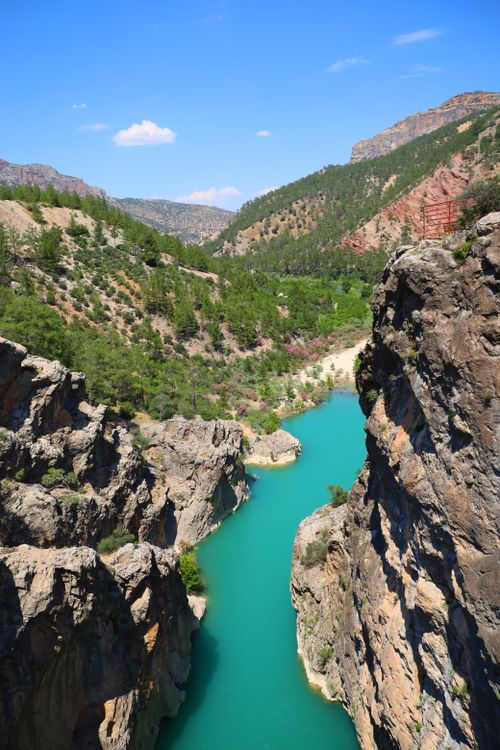 Free A breathtaking view of a canyon with a turquoise river flowing through it, surrounded by lush greenery. Stock Photo