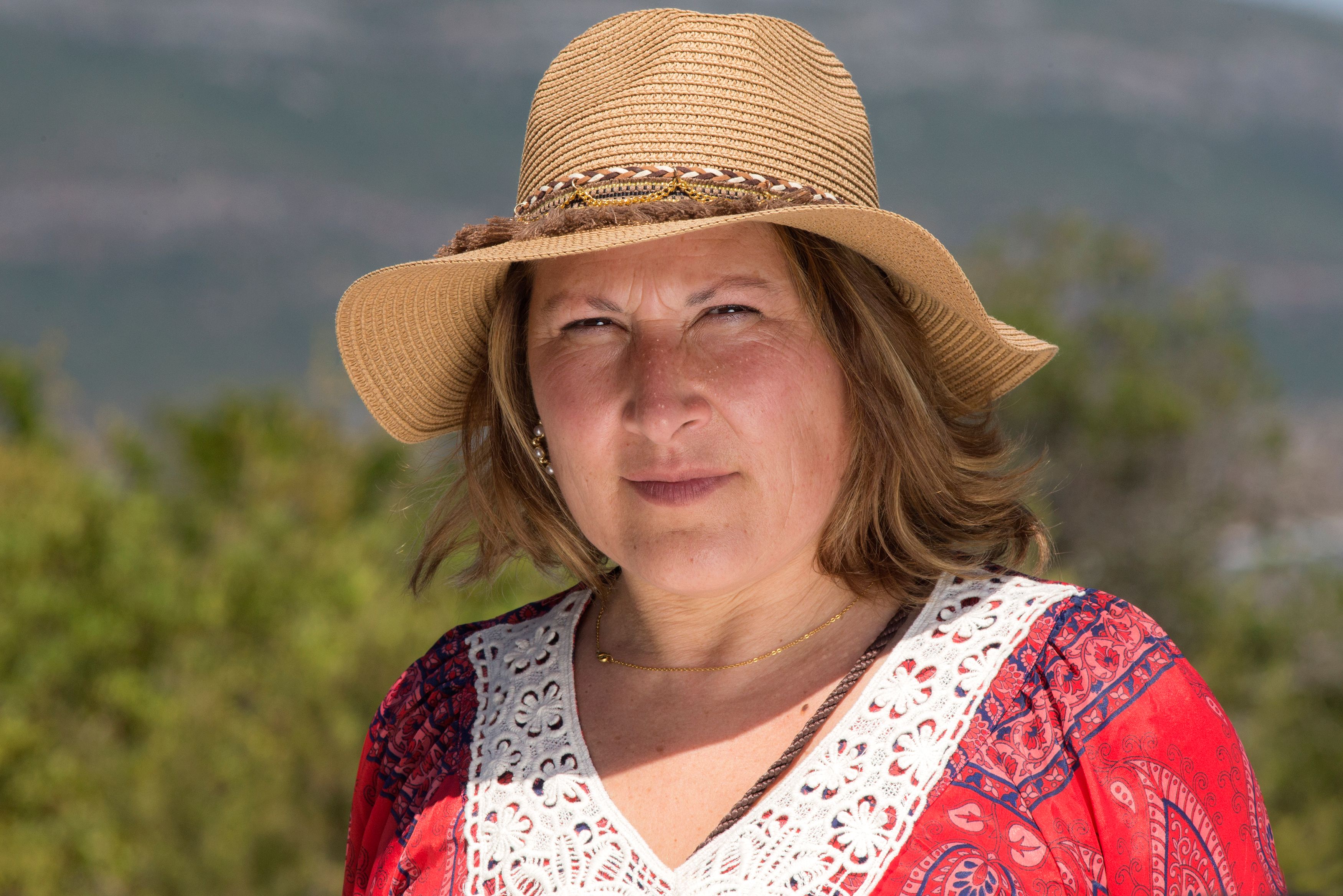 Portrait of a woman wearing a straw hat outdoors in natural light.