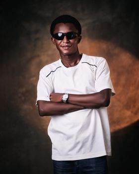 Portrait of a confident man wearing sunglasses, crossed arms, neutral expression, indoors.