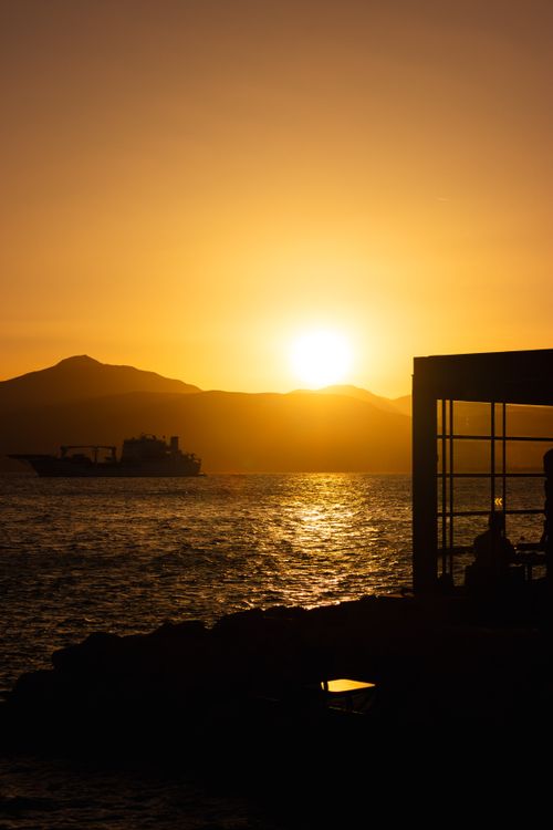 Free A mesmerizing sunset in Greece over the sea with a ferry and silhouettes. Stock Photo