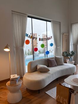 Contemporary living room with 'Happy Birthday' banner and colorful balloons, offering a cozy vibe.
