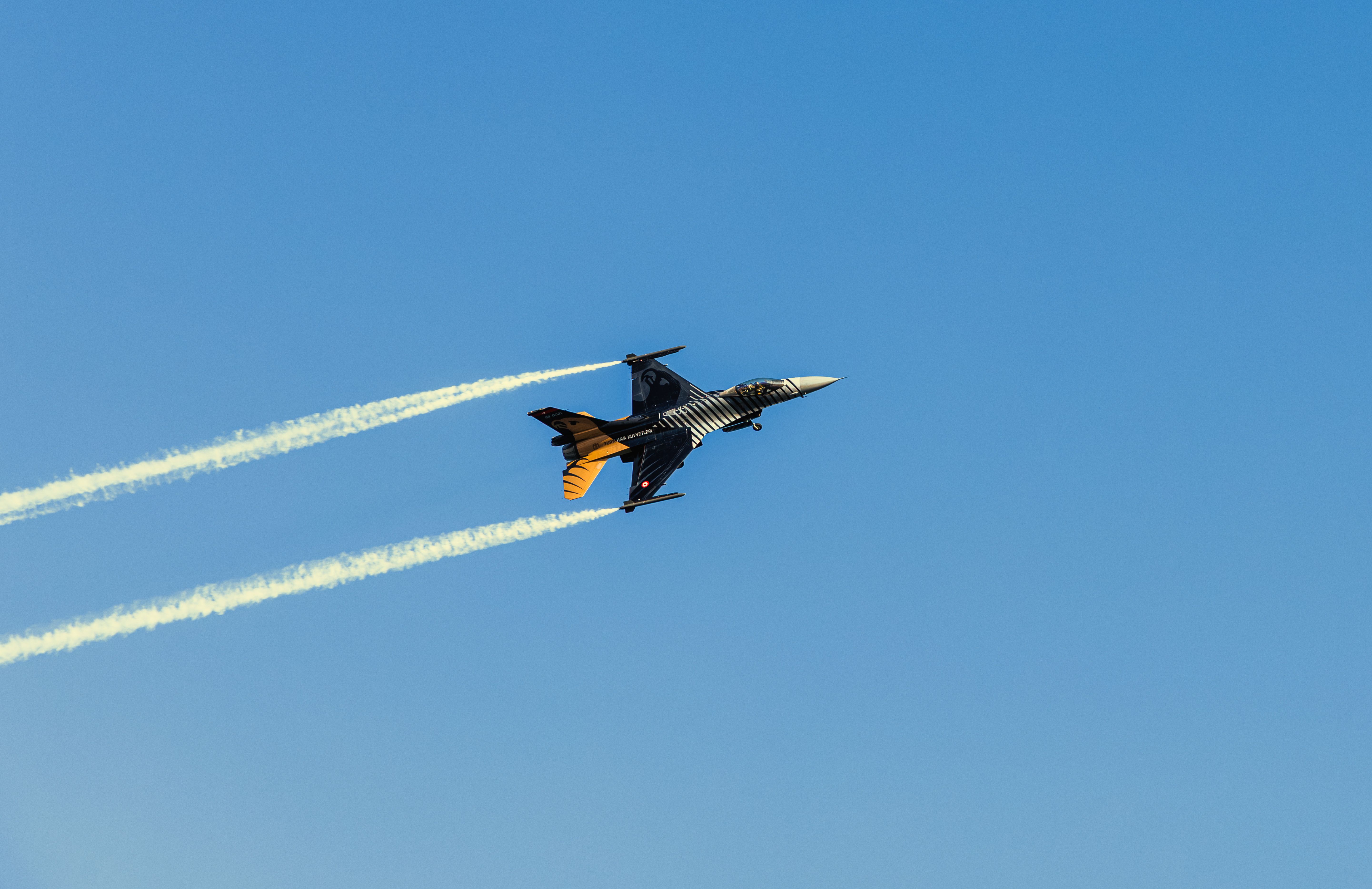 Military jet executing aerial stunt against clear blue sky, showcasing speed and agility.