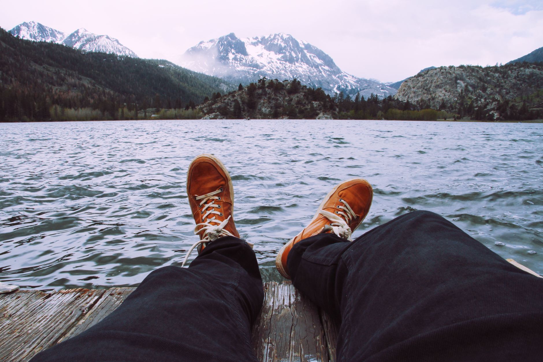 Person relaxing by June Lake with snowy mountain views in the background.