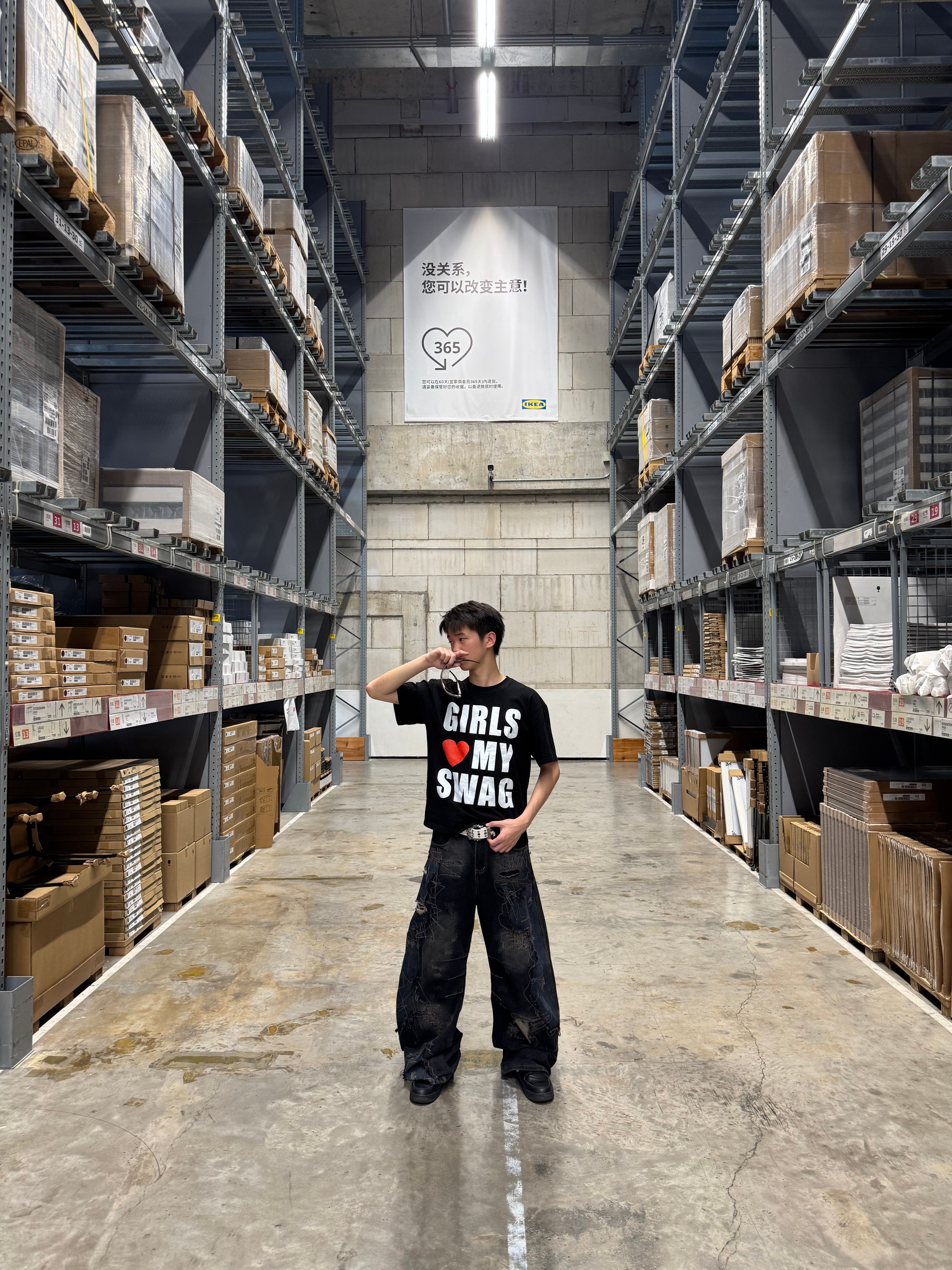 Young adult posing in a large industrial warehouse with stocked shelves.