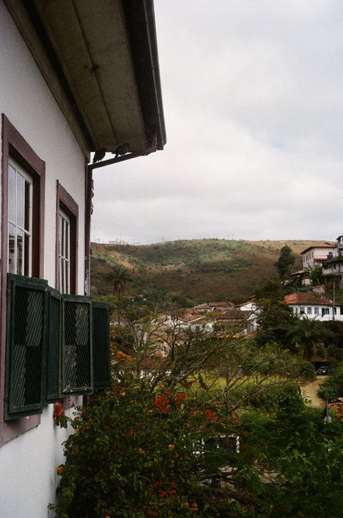 Free Scenic view from a colonial window towards rolling hills and charming houses. Stock Photo