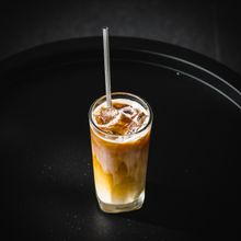 Creamy iced coffee in a tall glass with a metal straw — photo by Elle Kwee on Pexels