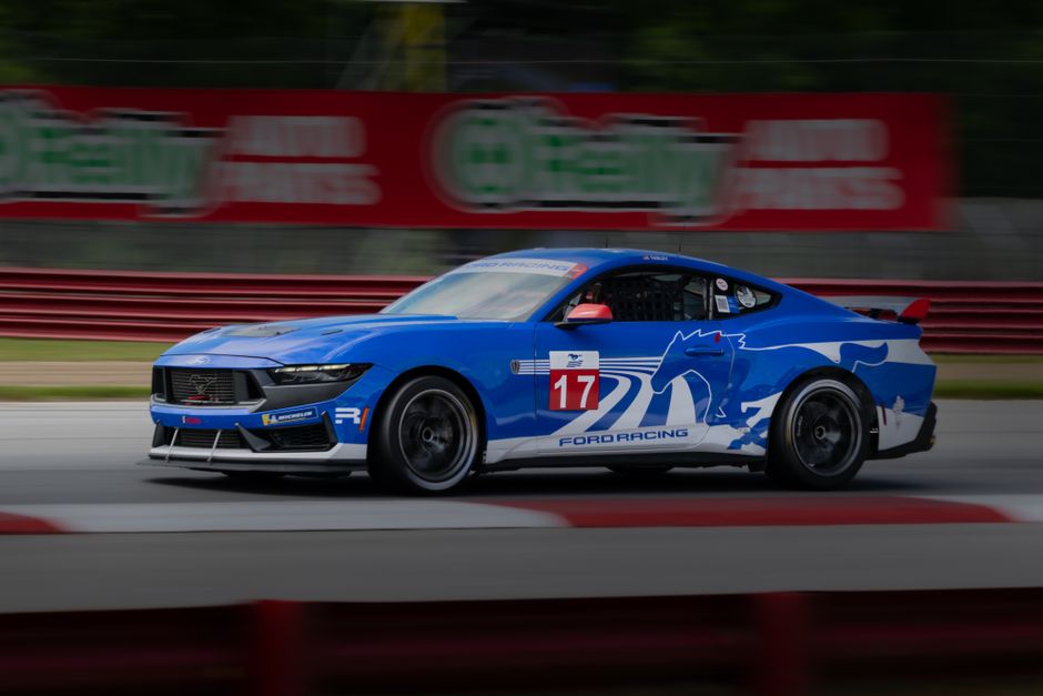 Blue Ford racing car speeding on a track in Lexington, Ohio, showcasing dynamic motion and automotive power.