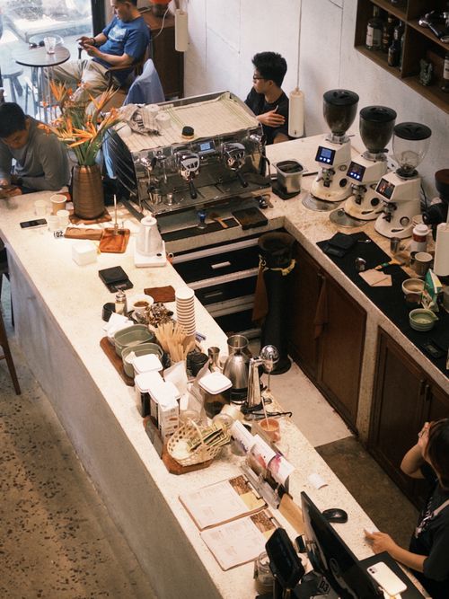 Free Aerial shot of a bustling cafe with baristas at work and customers enjoying coffee. Stock Photo