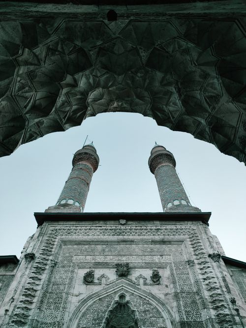 Free Architectural view of grand mosque minarets framed by intricate arch design in Sivas. Stock Photo