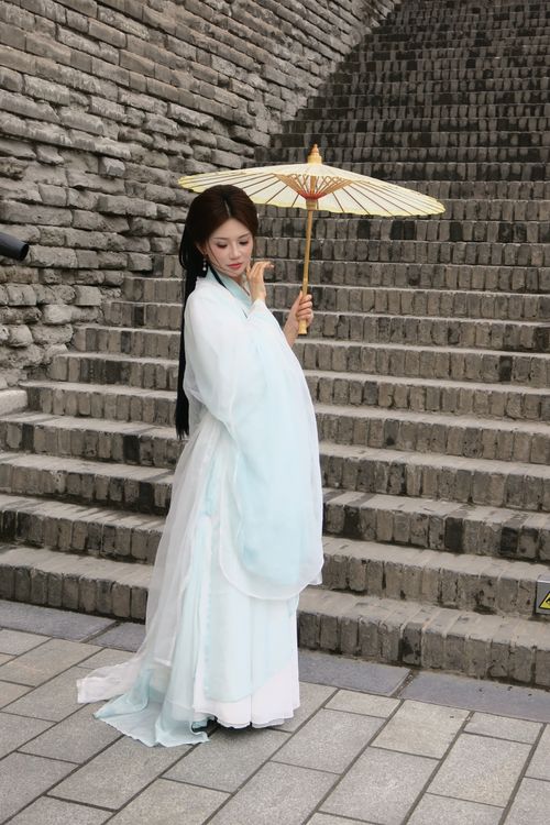Free A woman in traditional attire holding a parasol, standing on stone steps outdoors. Stock Photo