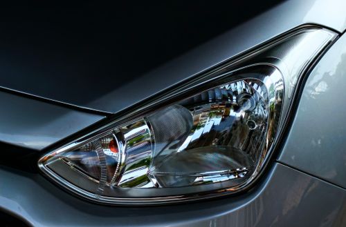 Free Detailed close-up of a car headlight on a sleek silver vehicle, showing intricate reflective elements. Stock Photo