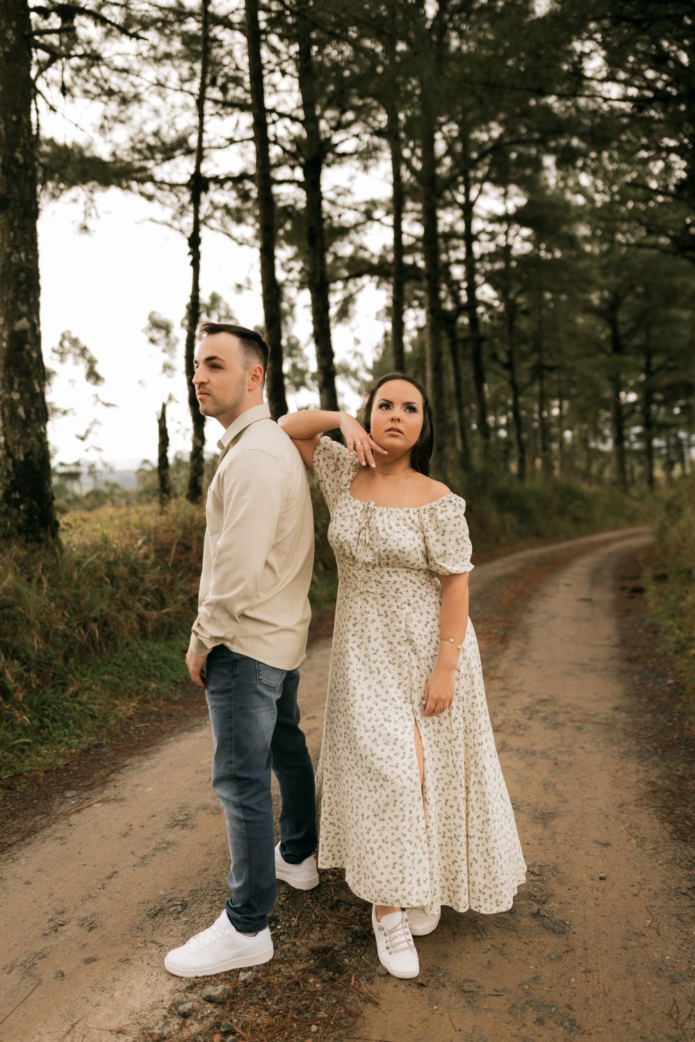 Stylish couple posing romantically on a dirt path in a serene forest