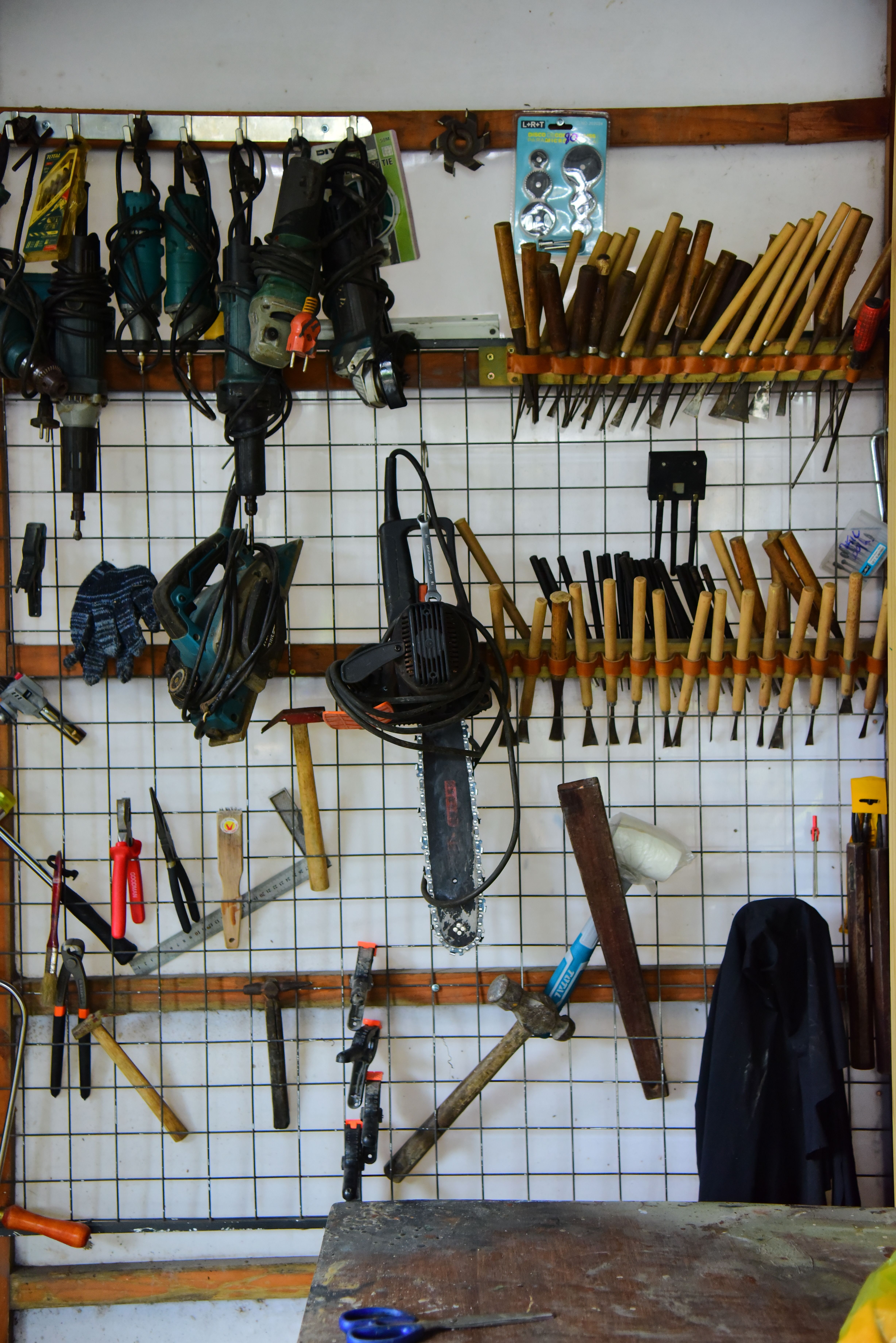 Neatly organized tools hanging on a workshop wall, showcasing various hand tools and power tools.