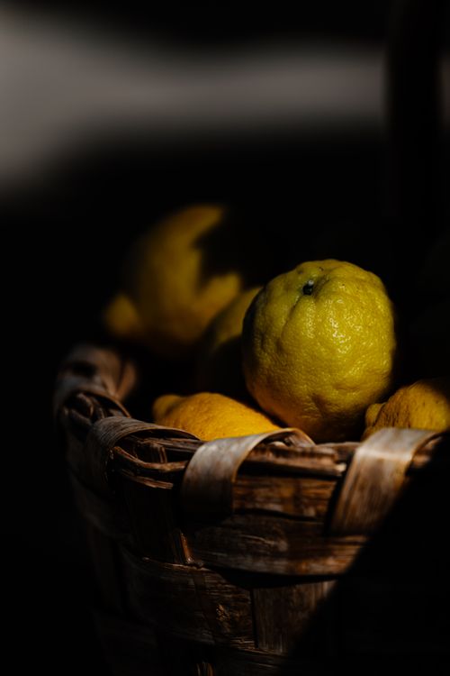 Free Artistic shot of lemons in a rustic basket with moody lighting, showcasing a blend of textures and Mediterranean flavors. Stock Photo