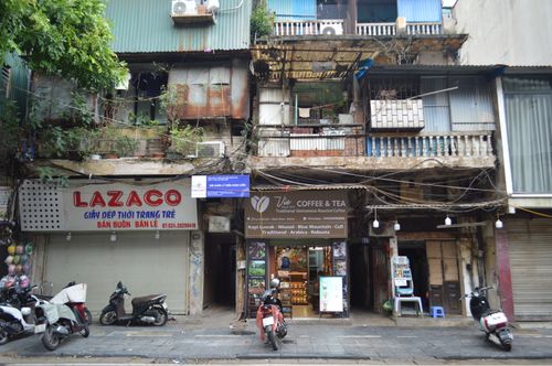 Free Authentic Vietnamese street scene with rustic shops and motorbikes parked along the sidewalk. Stock Photo