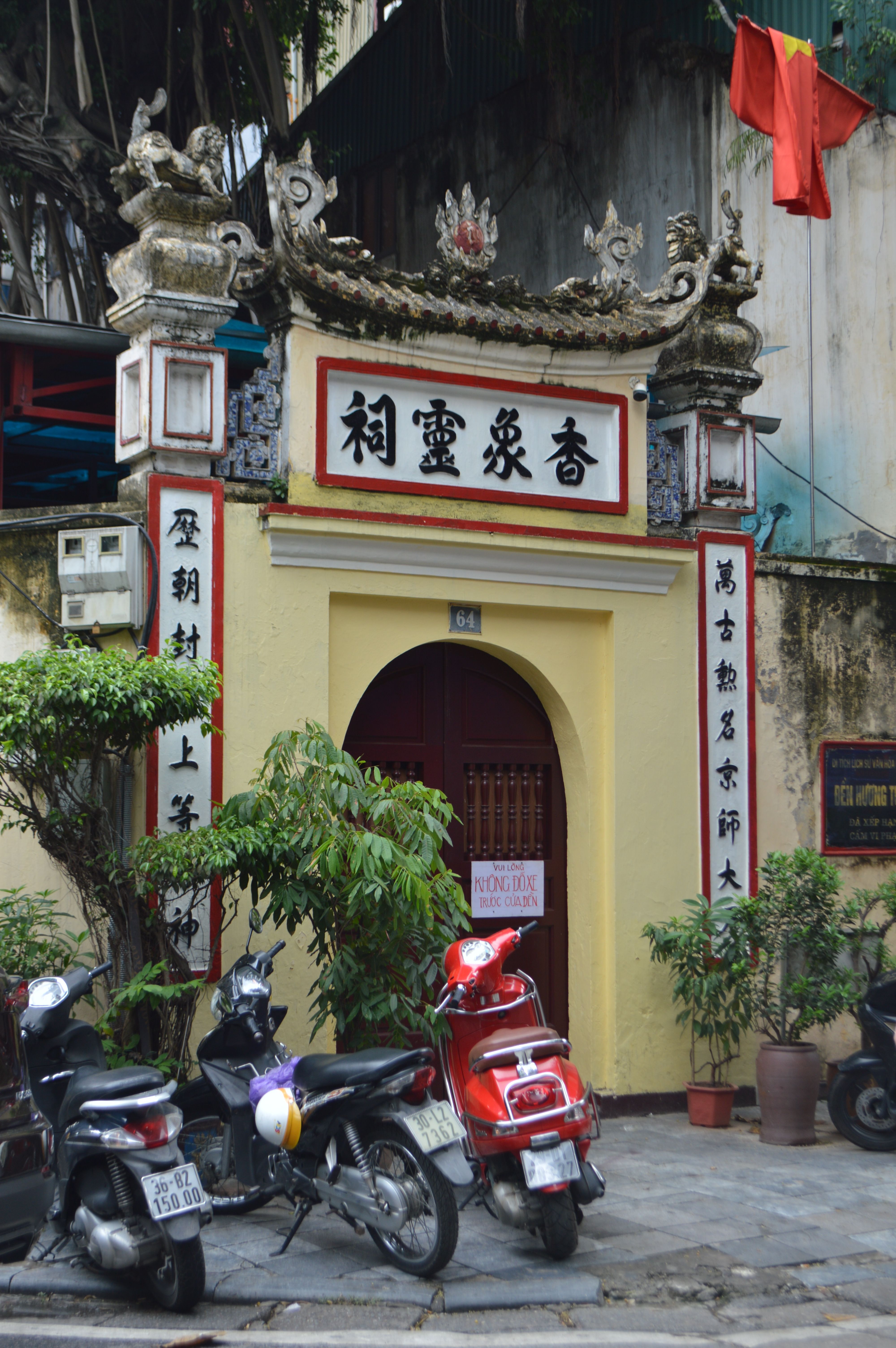 A view of a traditional Vietnamese temple entrance with scooters parked in front.