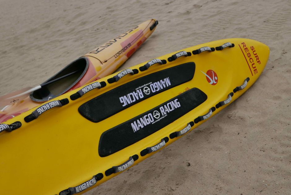 Close-up of a yellow surf rescue kayak on a sandy beach in Hong Kong.
