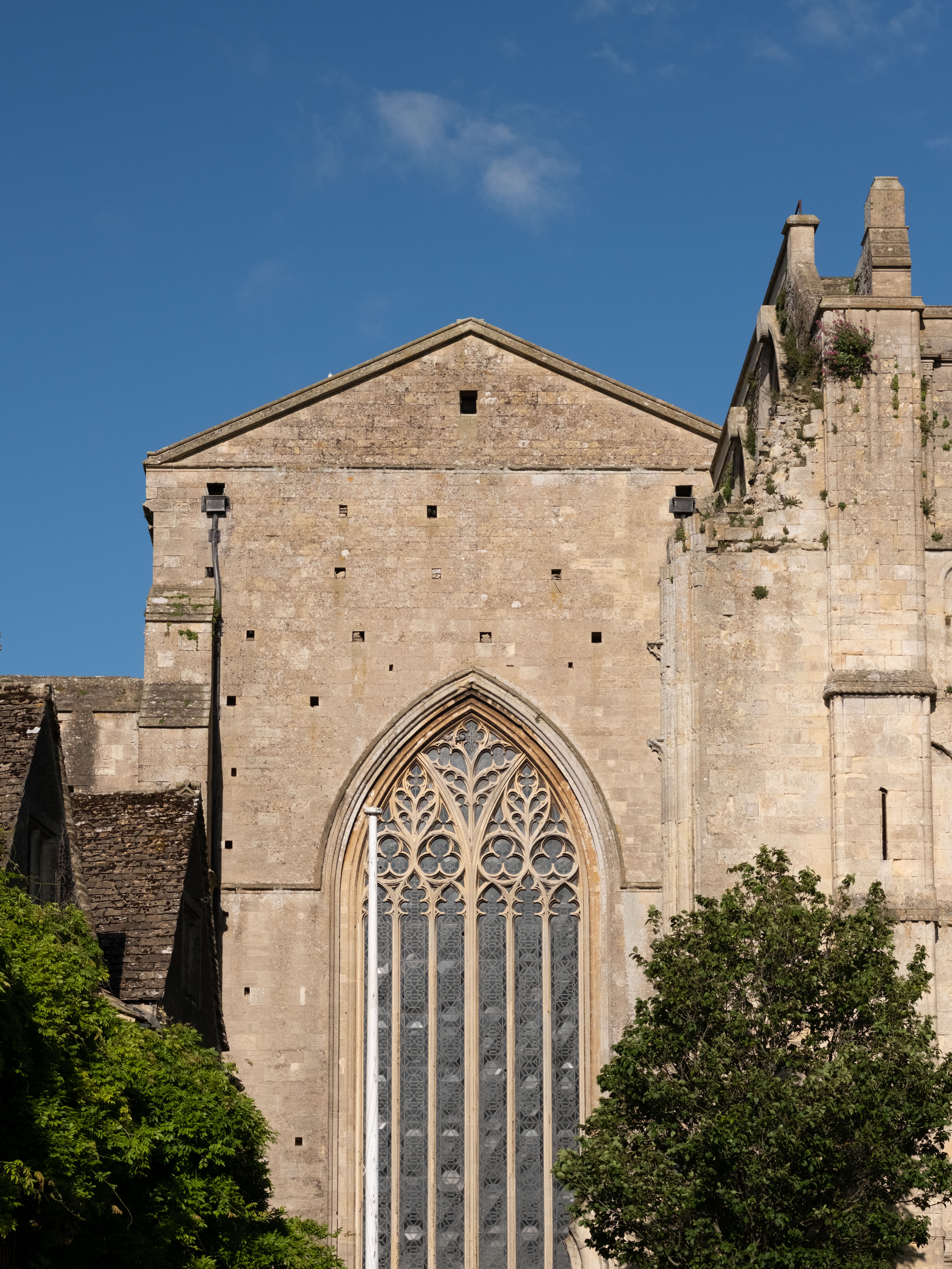 Capture the grandeur of Malmesbury Abbey's Gothic architecture on a striking sunny day.