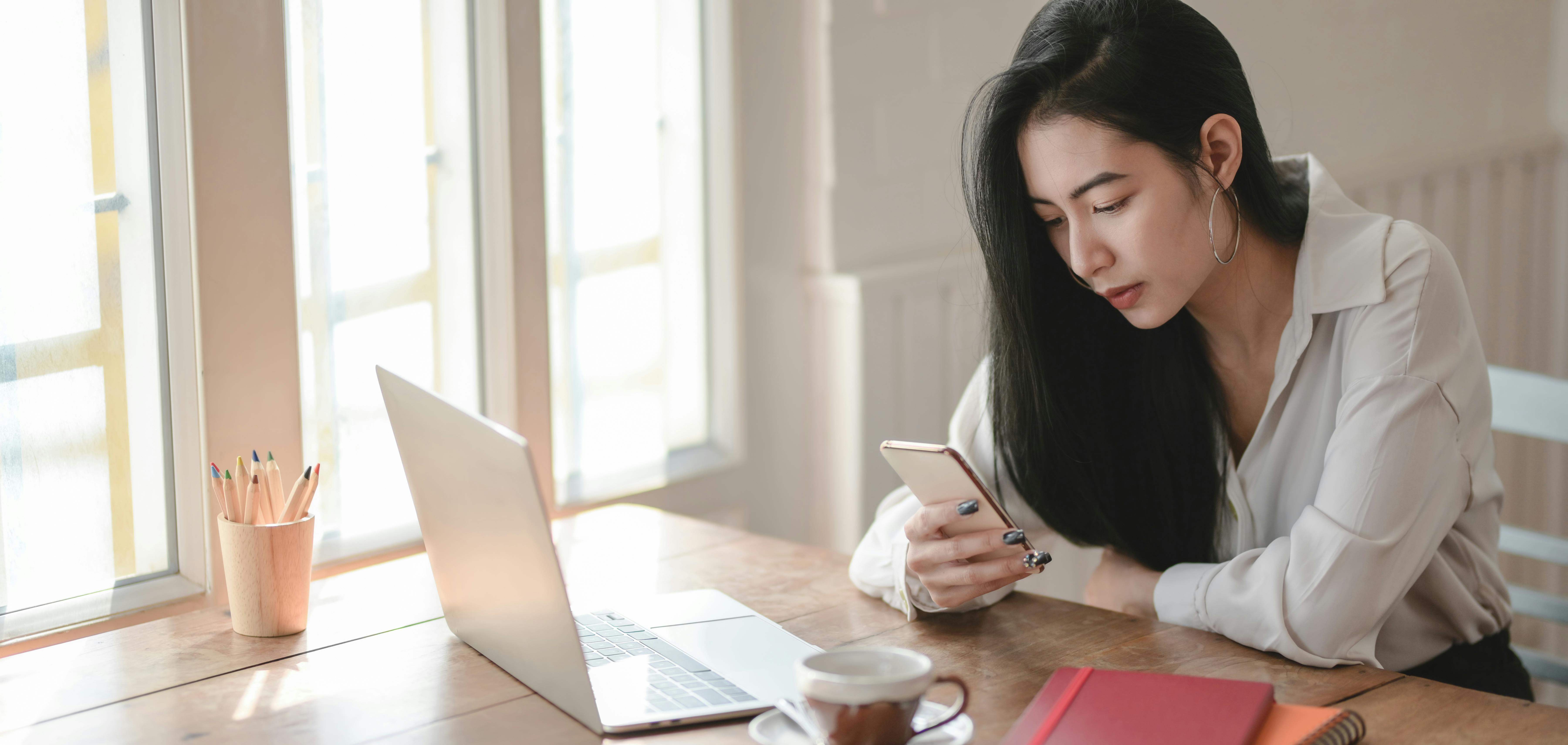 Woman in White Long Sleeve Shirt Using Smartphone