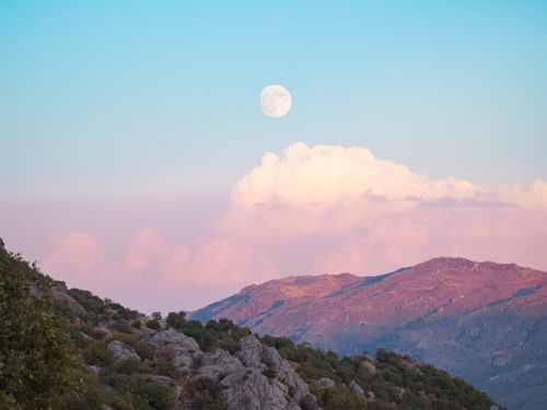 Free Scenic view of mountains under a full moon with pink clouds, providing a tranquil mood. Stock Photo