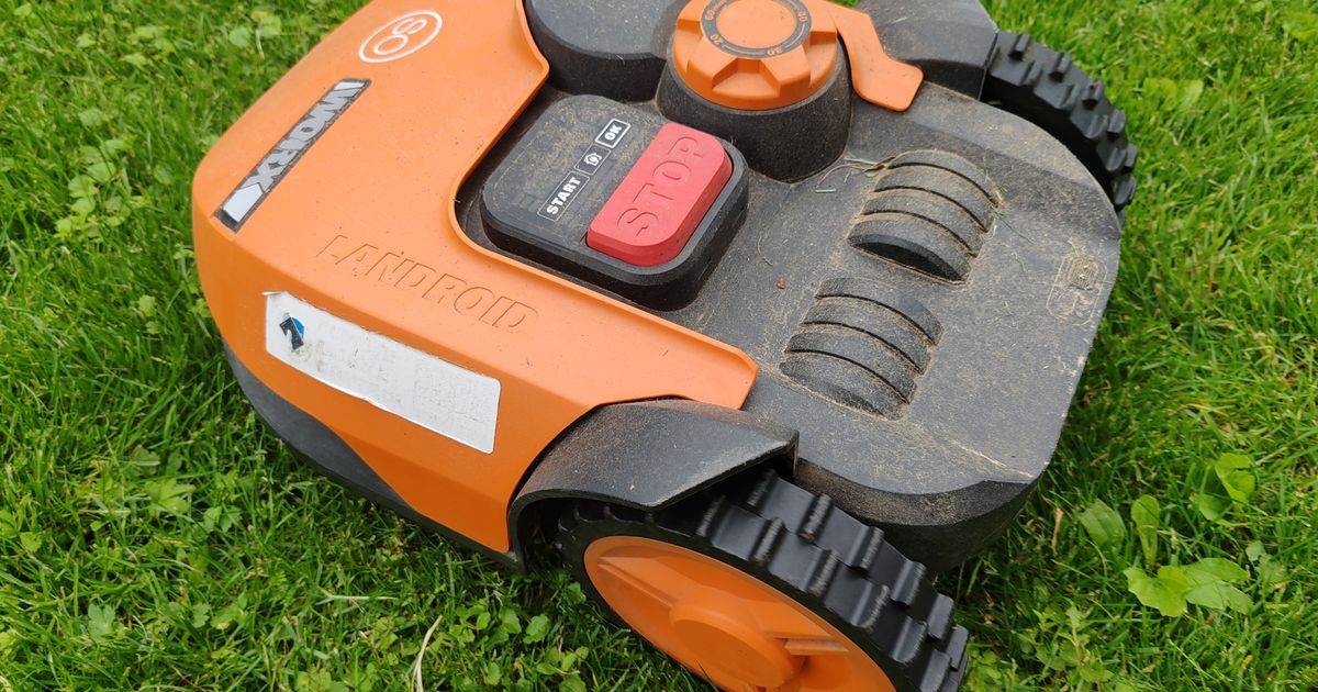 Robot tondeuse orange sur une pelouse fraîchement tondue