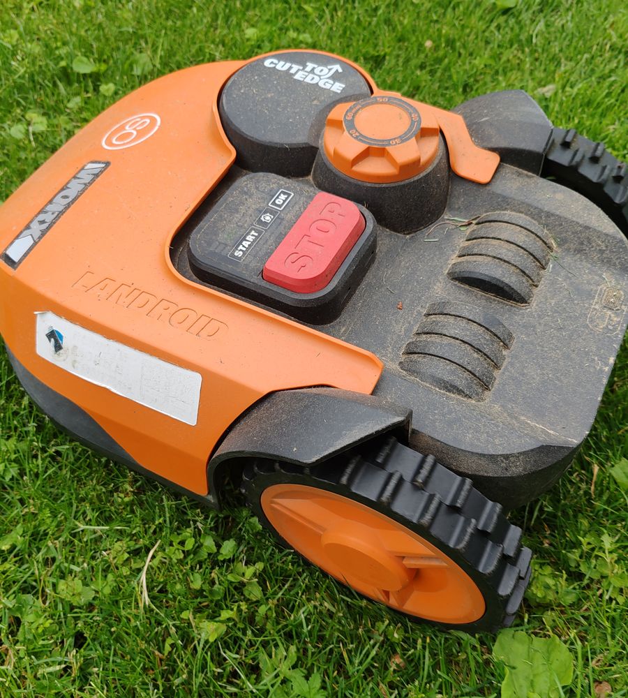 Robot tondeuse orange sur une pelouse fraîchement tondue