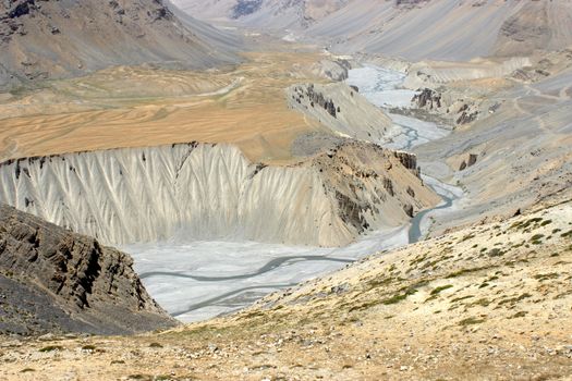 A breathtaking view of a winding river valley in Himachal Pradesh, India, showcasing dramatic cliffs and rugged terrain.