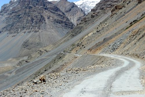 Free Dramatic winding road through rocky mountain landscape under clear blue sky. Stock Photo