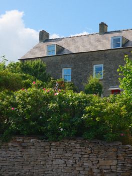 A picturesque stone cottage surrounded by lush greenery in Malmesbury, England.
