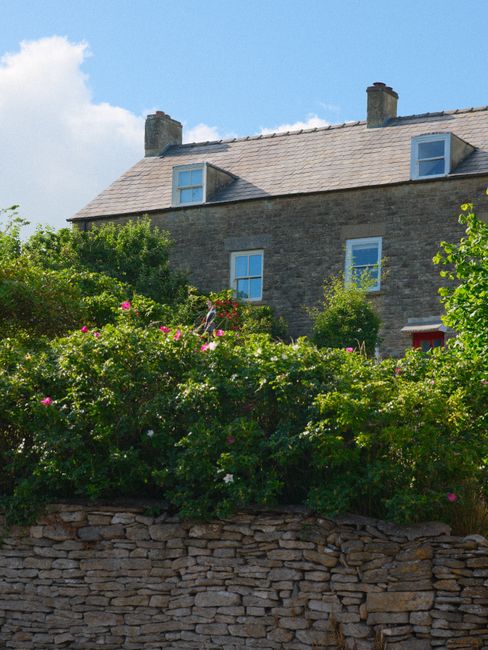 A picturesque stone cottage surrounded by lush greenery in Malmesbury, England.