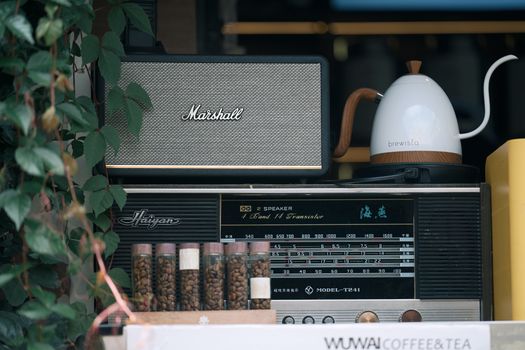 A stylish setup featuring a vintage radio, speaker, and a modern kettle with tea leaves.