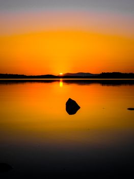 Captivating sunset view over calm lake with a vibrant orange sky in Ireland.