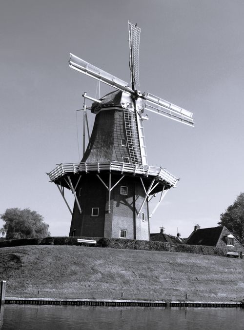 Free Black and white photo of a traditional Dutch windmill on a grassy hill under a clear sky. Stock Photo