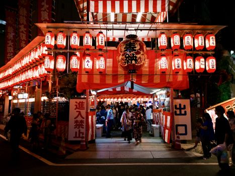 Colorful Japanese festival with lanterns and people in traditional clothing at night.