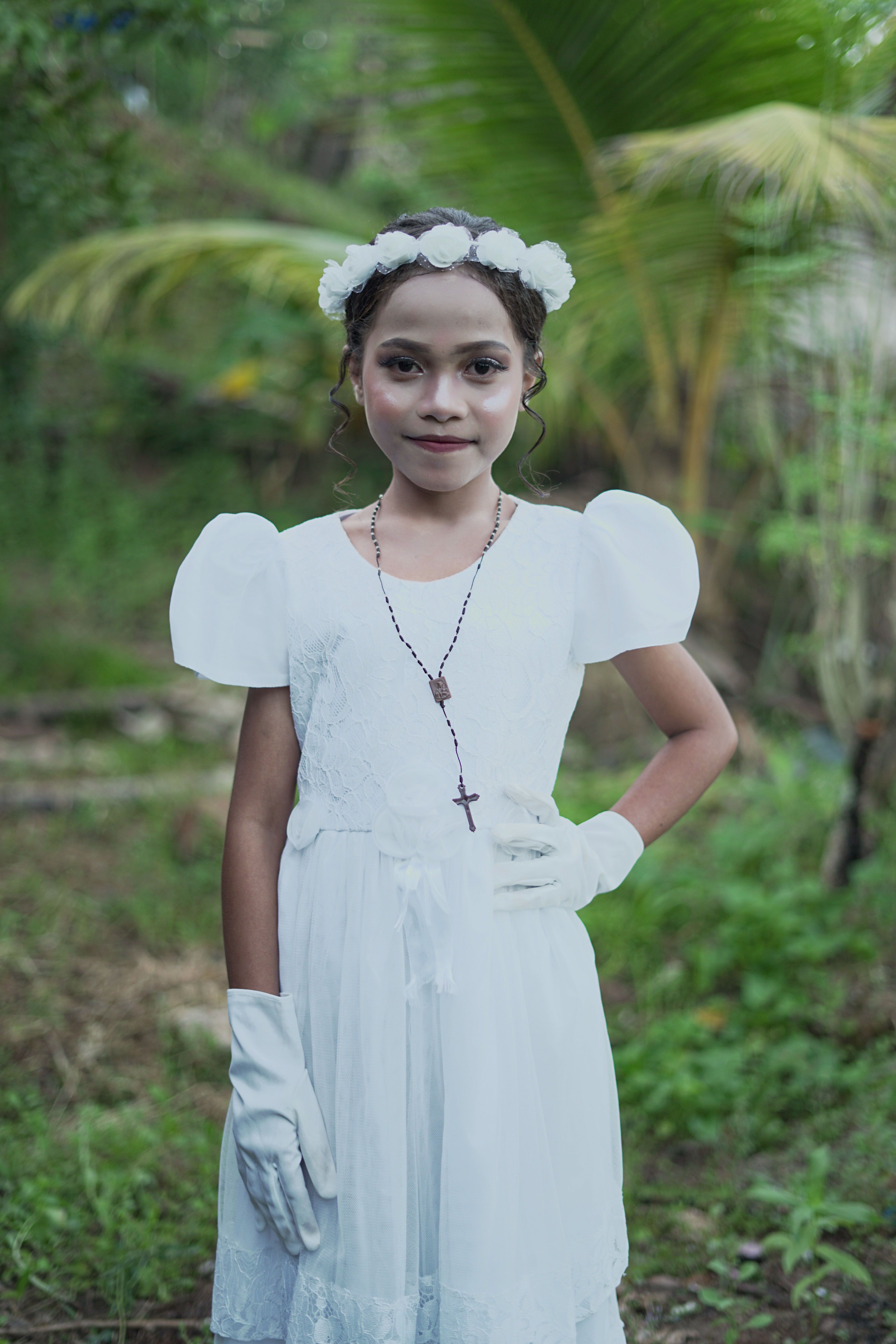 A young girl in a white dress poses outdoors in East Nusa Tenggara, Indonesia.