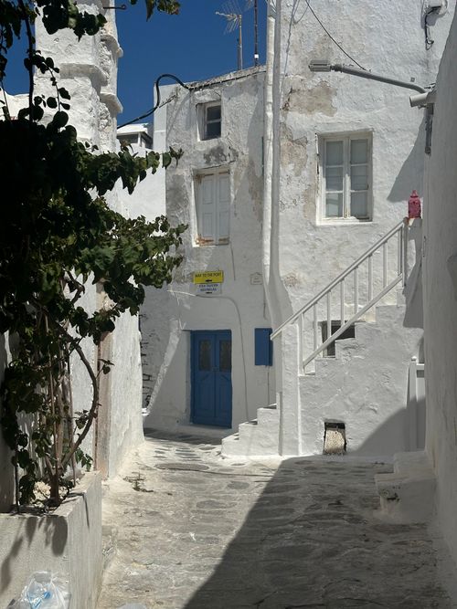 Free Explore a serene Cycladic alleyway in Greece, showcasing classic white architecture and blue accents. Stock Photo