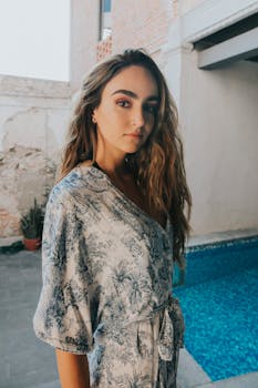 一位身着花裙的年轻女子站在泳池边，显得优雅而自信