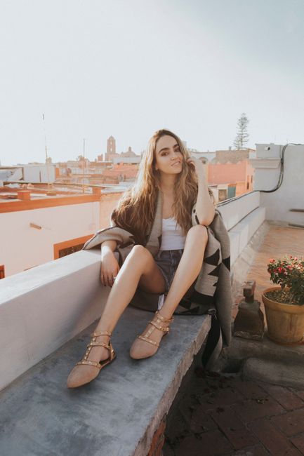 A fashionable woman sits on a rooftop in Santiago de Querétaro, Mexico, enjoying a sunny day.