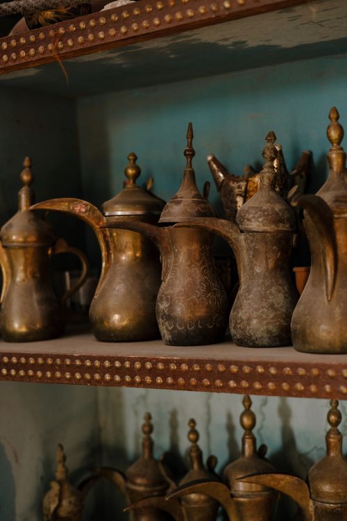 Free Antique brass coffee pots showcased on a teal shelf, reflecting Middle Eastern culture. Stock Photo
