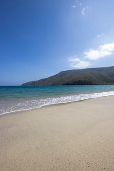 Pristine beach landscape with clear blue sky and distant hills. Perfect for relaxation themes.