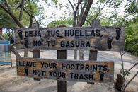 Wooden sign promoting nature preservation in a lush outdoor area.