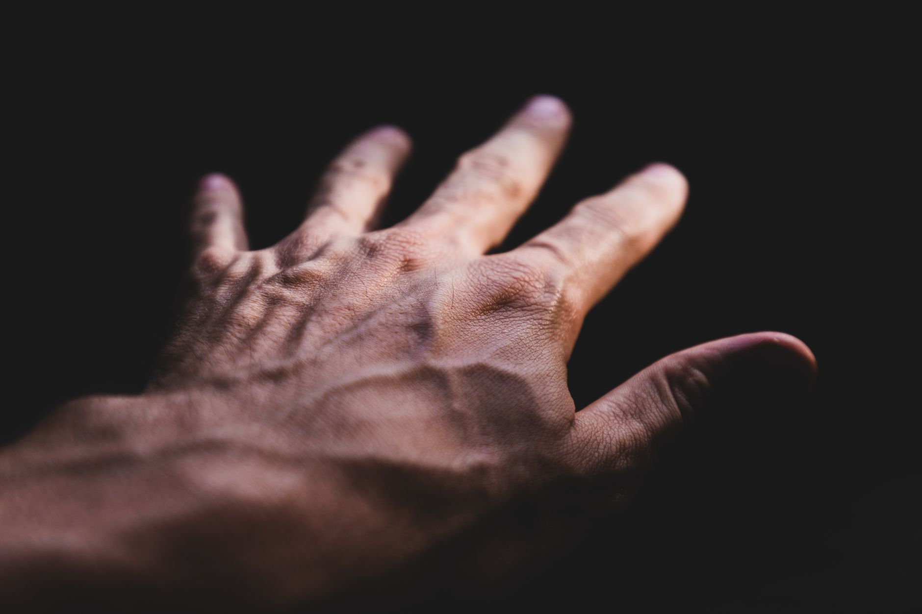 Detailed image of a human hand showing prominent veins against a dark background.