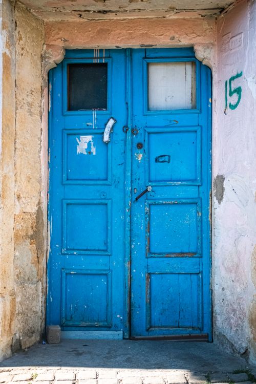 Free Old blue door on rustic building, displaying weathered textures and vibrant color. Perfect for architectural studies. Stock Photo