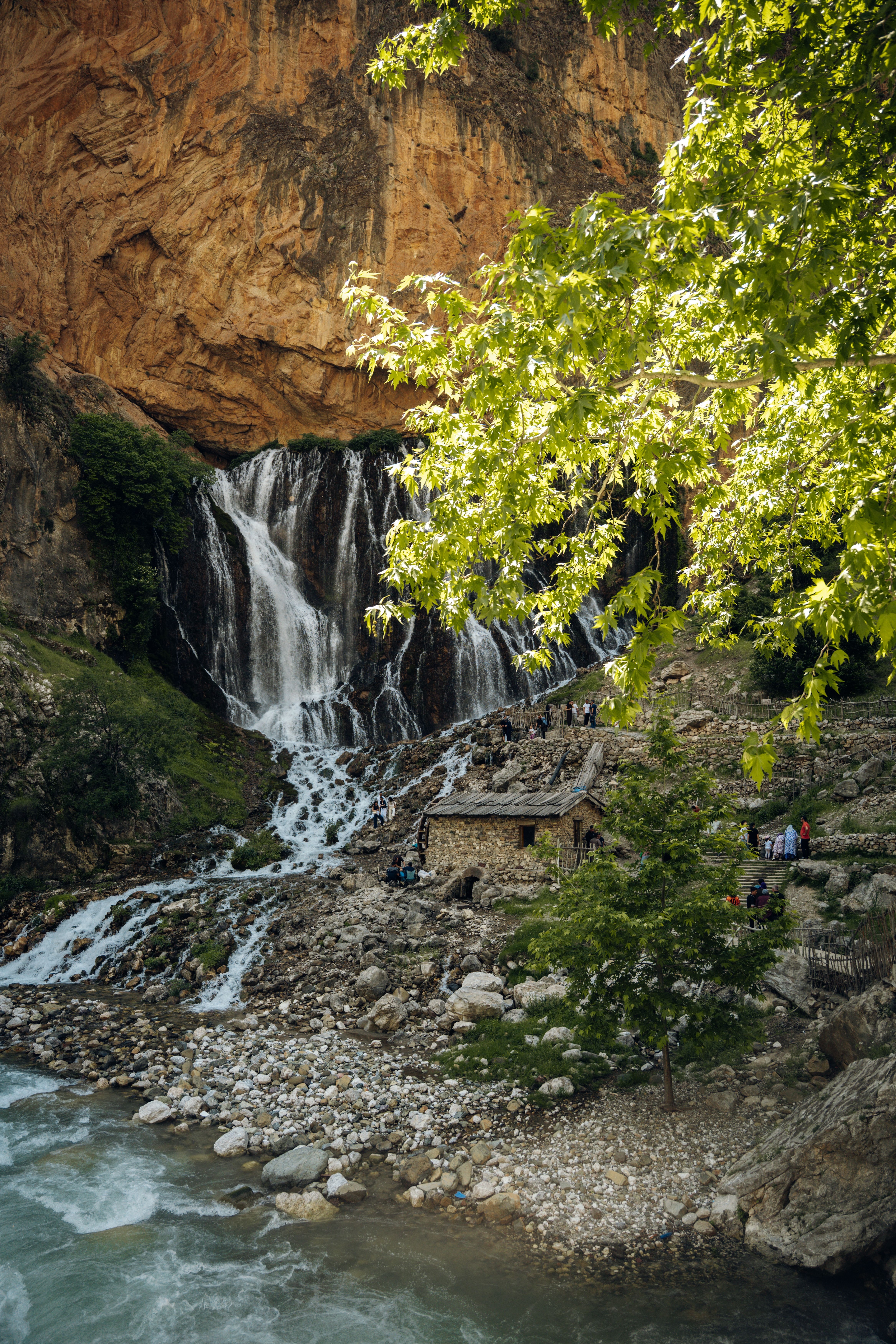 A captivating waterfall cascades down a rocky backdrop surrounded by vibrant greenery, creating a tranquil natural scene.