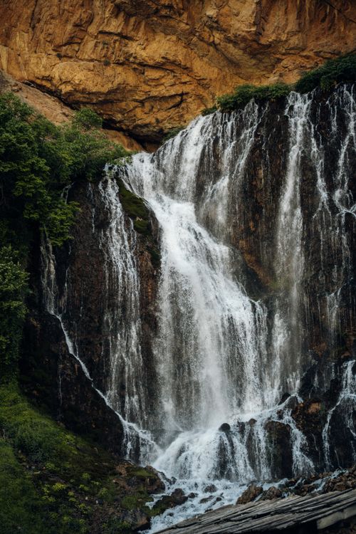 Free A majestic waterfall cascading down rocky cliffs surrounded by lush greenery. Stock Photo