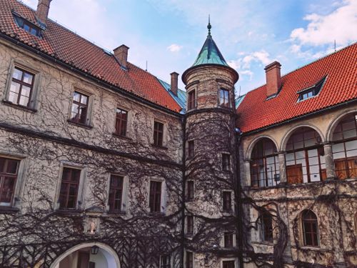 Free Historic castle courtyard in Turnov, Czech Republic with ivy-covered walls and red-tiled roofs. Stock Photo