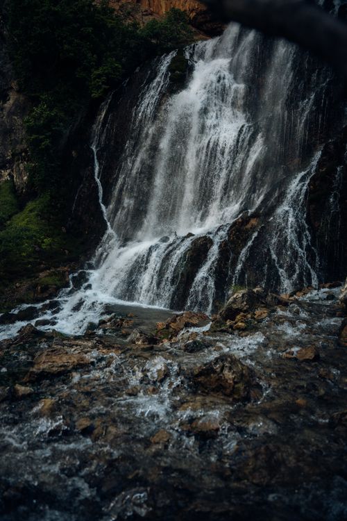 Free A captivating waterfall cascading over rocks surrounded by lush greenery. Stock Photo