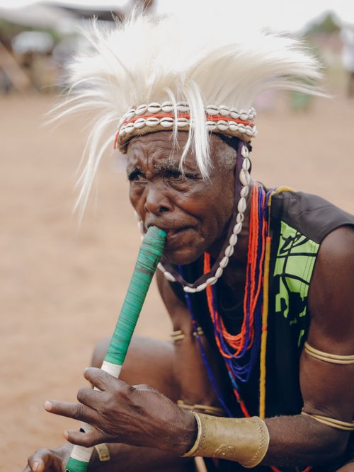 Free Elderly musician in traditional attire playing a wind instrument outdoors. Stock Photo